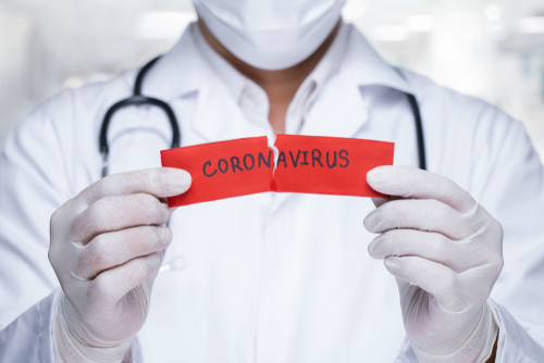 Picture of a male Physician wearing gloves and holding a ripped piece of paper that says: CORON|AVIRUS